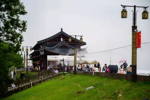 堤坝上仿古楼阁水雾下游客憩息